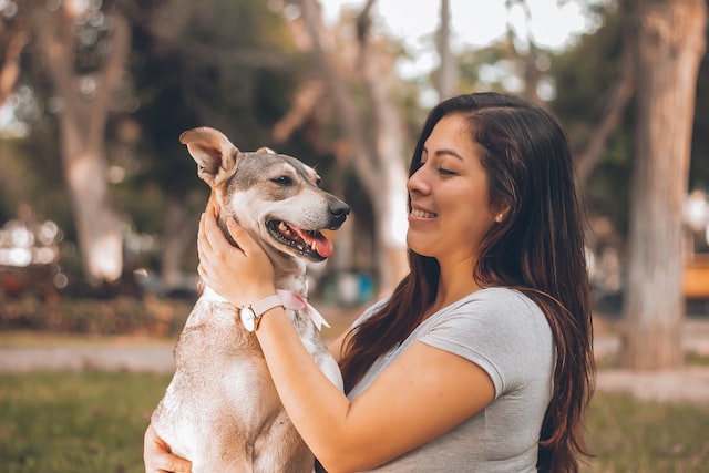 Woman hugging her dog while it sticks its tongue out